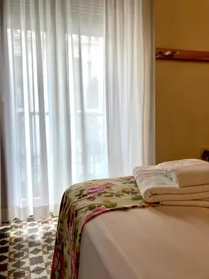 a bedroom with a bed and a window with white curtains at Casa de Huéspedes Santa Maria in El Puerto de Santa María