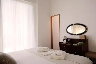 a bedroom with a bed with a mirror and towels at Casa de Huéspedes Santa Maria in El Puerto de Santa María