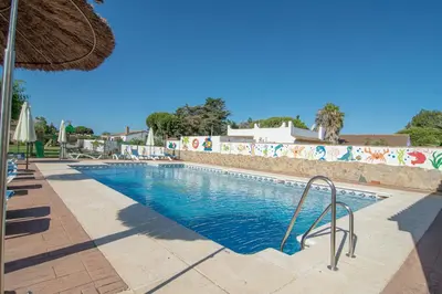 a swimming pool at a resort with an umbrella at Apartamentos El Palmeral in Conil de la Frontera