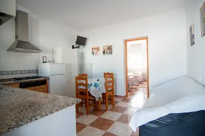 a kitchen with a counter and a kitchen with a table at Apartamentos El Palmeral in Conil de la Frontera