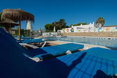a group of blue lounge chairs next to a swimming pool at Apartamentos El Palmeral in Conil de la Frontera