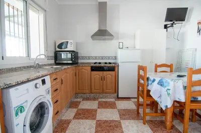 a kitchen with a washing machine and a table at Apartamentos El Palmeral in Conil de la Frontera