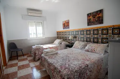 a bedroom with two beds and a table and a chair at Apartamentos El Palmeral in Conil de la Frontera