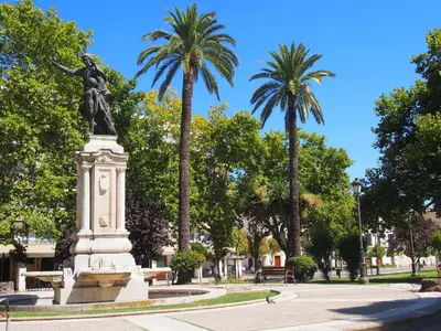 a statue of a woman in a park with palm trees at Casa Valientes B - Parking privado gratis & patio interior in Jerez de la Frontera