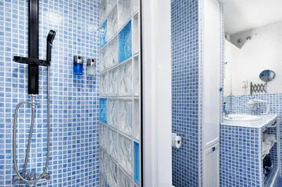 a blue tiled bathroom with a shower and a sink at El Marinero in Rota