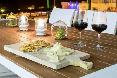 a wooden table with two glasses of wine and a cutting board at Panther Home Manantial in El Puerto de Santa María