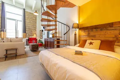 a bedroom with a large bed and a spiral staircase at Entre Bodegas Jerez in Jerez de la Frontera