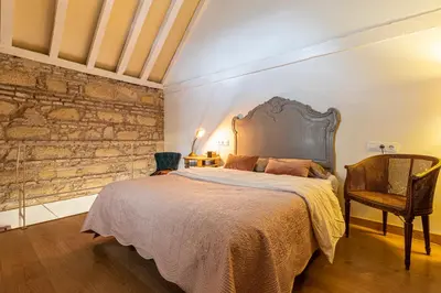 a bedroom with a large bed and a stone wall at Entre Bodegas Jerez in Jerez de la Frontera