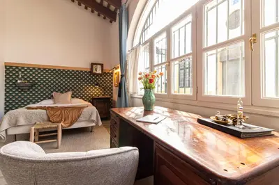 a bedroom with a bed and a desk with a vase of flowers at Entre Bodegas Jerez in Jerez de la Frontera