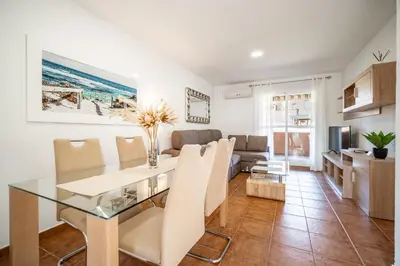 a dining room and living room with a table and chairs at Precioso Apartamento Jardin del Golf 1, Novo Sancti Petri in Chiclana de la Frontera