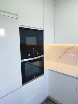 a kitchen with white cabinets and black appliances at Precioso Apartamento Jardin del Golf 1, Novo Sancti Petri in Chiclana de la Frontera