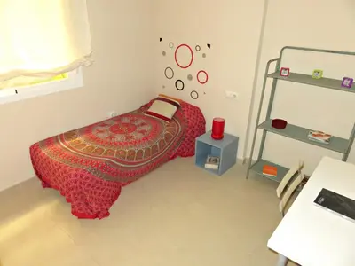 a bedroom with a bed with a red blanket and a table at Apartamento barrio San Miguel in Jerez de la Frontera