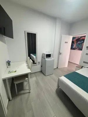 a bedroom with a bed and a desk and a microwave at Hostal Los Mellizos in Conil de la Frontera
