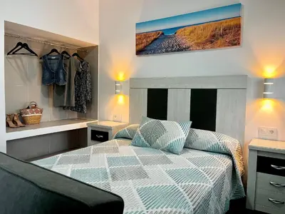a bedroom with a bed and a chair in it at Hostal Los Mellizos in Conil de la Frontera