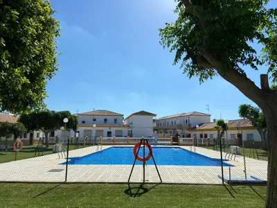 a swimming pool with a tree in front of a building at Hostal Los Mellizos in Conil de la Frontera