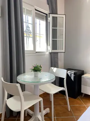 a table and chairs in a room with a window at Hostal Los Mellizos in Conil de la Frontera
