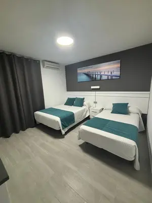 a bedroom with two beds and a wall at Hostal Los Mellizos in Conil de la Frontera