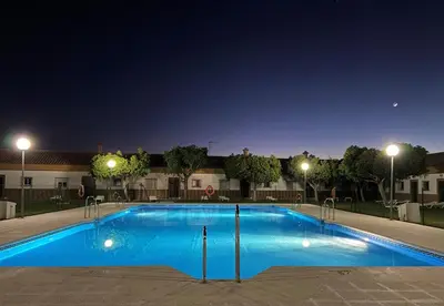 a large blue swimming pool at night with lights at Apartamentos Los Mellizos in Conil de la Frontera