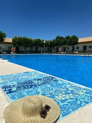 a straw hat sitting on the edge of a swimming pool at Apartamentos Los Mellizos in Conil de la Frontera