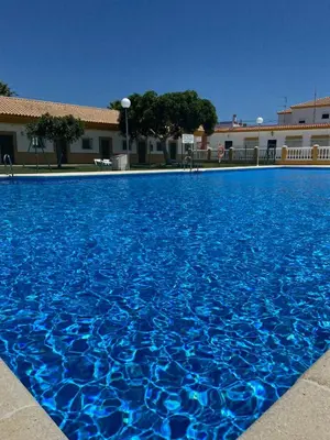 a large blue swimming pool in front of a building at Apartamentos Los Mellizos in Conil de la Frontera