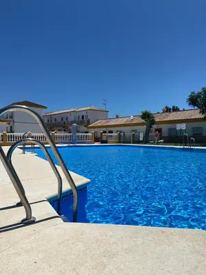 a large swimming pool with a metal handrail next to a building at Apartamentos Los Mellizos in Conil de la Frontera