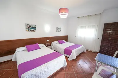 a bedroom with two beds and a table and a window at Apartamentos Los Mellizos in Conil de la Frontera