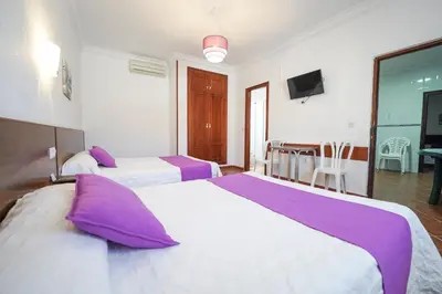 a hotel room with two beds with purple pillows at Apartamentos Los Mellizos in Conil de la Frontera
