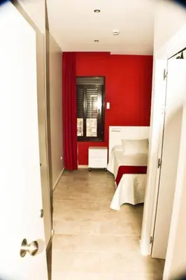 a hallway with two beds in a red room at Hostal Playa Candor in Rota