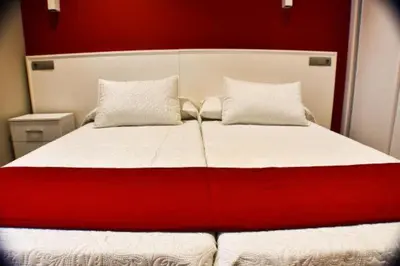 a red and white bed with two pillows on it at Hostal Playa Candor in Rota