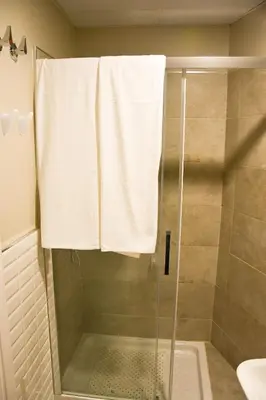 a bathroom with a shower with a glass door at Hostal Playa Candor in Rota