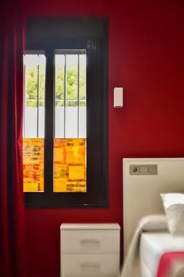 a red room with a window and a bed at Hostal Playa Candor in Rota