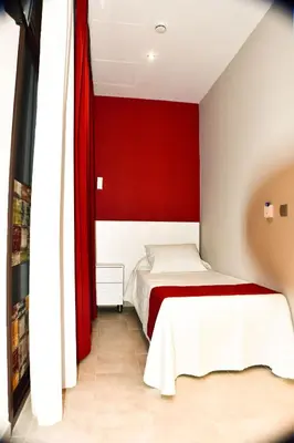 a bedroom with a red wall and two beds at Hostal Playa Candor in Rota