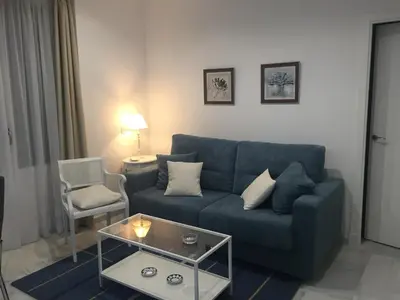 a living room with a blue couch and a table at Apartamento Calle Nueva in Cádiz