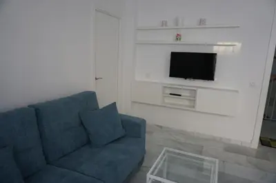 a living room with a blue couch and a flat screen tv at Apartamento Calle Nueva in Cádiz