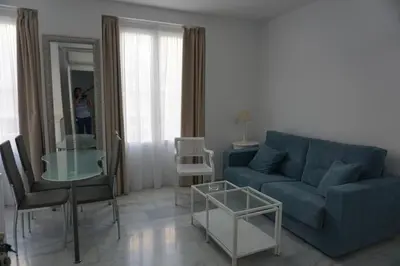 a living room with a blue couch and a glass table at Apartamento Calle Nueva in Cádiz