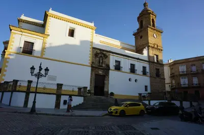 a yellow car parked in front of a building with a clock tower at Apartamento Calle Nueva in Cádiz