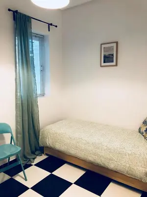 a bedroom with a bed and a chair and a window at Apartamento San Francisco in Cádiz