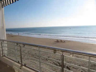 a beach with people on the sand and the ocean at Life Apartments Fuentebravía in El Puerto de Santa María