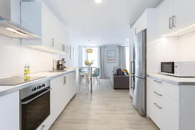 a kitchen with white appliances and a living room at Nueva ALMUDENA Apartment by Cadiz4Rentals in Cádiz