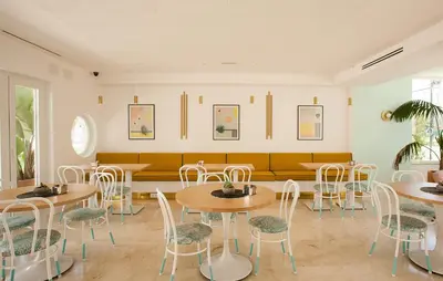 a restaurant with tables and chairs and a couch at Hostal Las Cumbres in Conil de la Frontera