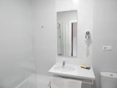 a white bathroom with a sink and a mirror at Hostal Las Cumbres in Conil de la Frontera