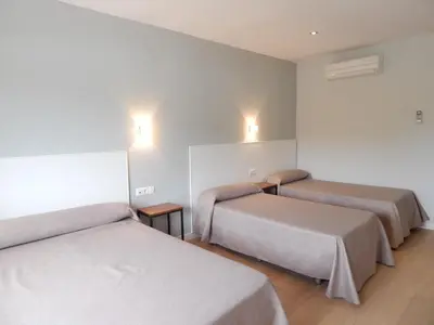 a room with three beds and lights on the wall at Hostal Las Cumbres in Conil de la Frontera