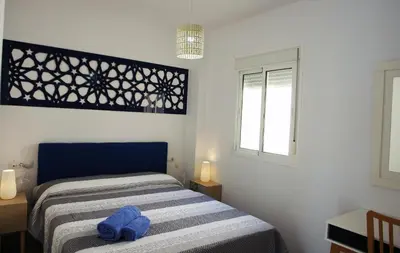 a small bedroom with a bed and a window at Apartamentos Costa de la Luz playa in Rota
