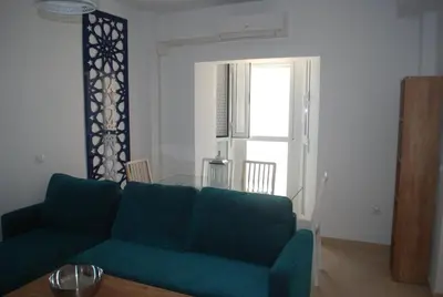a living room with a green couch and a glass table at Apartamentos Costa de la Luz playa in Rota