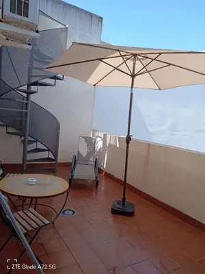 a patio with a table and an umbrella and a chair at Apartamentos Costa de la Luz playa in Rota
