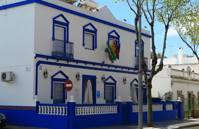a blue and white building with a tree in front at Hostal El Puerto Boutique in Chipiona