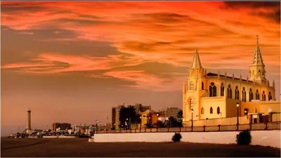 a large building with a sunset in the background at Hostal El Puerto Boutique in Chipiona
