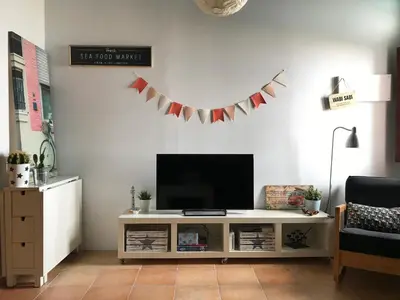 a living room with a television and a table at Preciosa casa baja con aire acondicionado in Sanlúcar de Barrameda