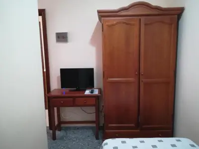 a bedroom with a wooden cabinet and a desk with a television at Vivienda Rural Alcazaba in Chipiona