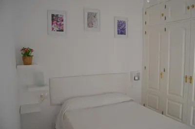 a white bedroom with a bed and some pictures on the wall at Beautiful Central Cadiz in Cádiz